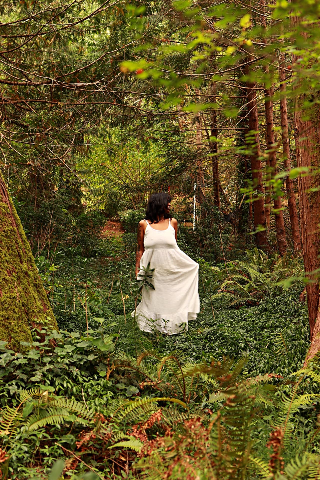 A woman in a white dress walking through the forest